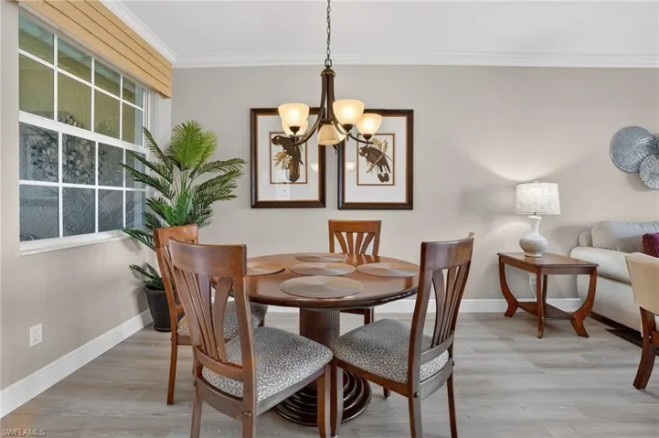 Dining room featuring light wood finished floors, ornamental molding, and hanging lights