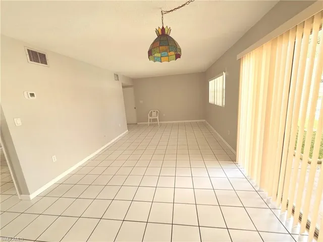 Spacious interior featuring ceramic tile flooring, light gray wall paint, and a stained-glass style ceiling light fixture