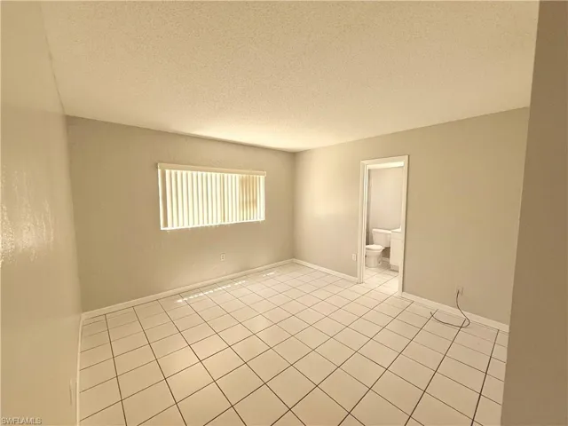 Spacious interior room featuring light-colored walls and a window with horizontal blinds