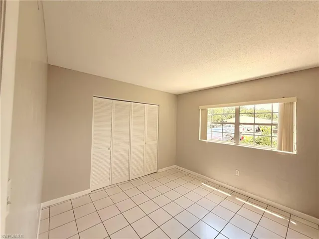 Neutral wall tones with white trim, ceramic tile flooring, and louvered closet doors