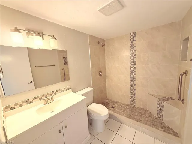 Walk-in shower with neutral-toned tiling, a decorative mosaic vertical accent, and a built-in bench