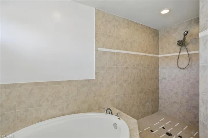 Primary Bathroom featuring a garden tub and a tile shower