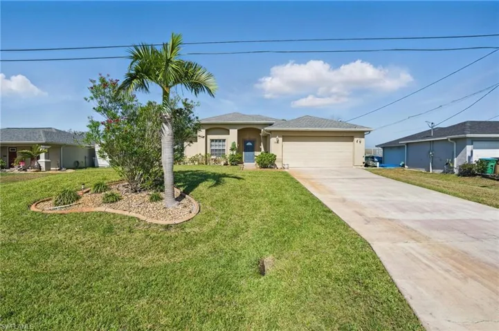 Single story home featuring a garage, a front yard, driveway