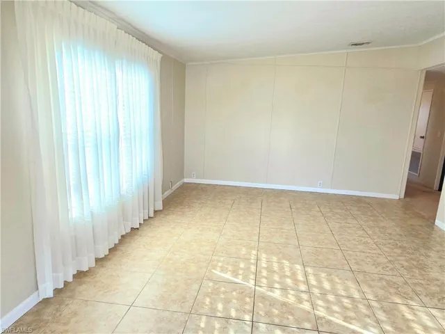 Empty room with light tile patterned flooring and baseboards