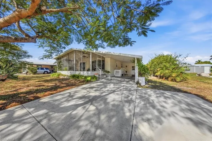 View of front of property with driveway, a carport, and a sunroom