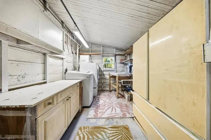 Washroom with lofted ceiling, concrete flooring, cabinet space, and separate washer and dryer