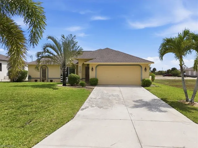 Ranch-style home with a front yard, a garage, driveway, and stucco siding