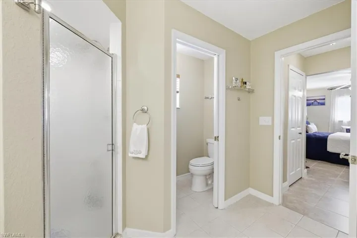 Ensuite bathroom featuring a stall shower and light tile patterned flooring