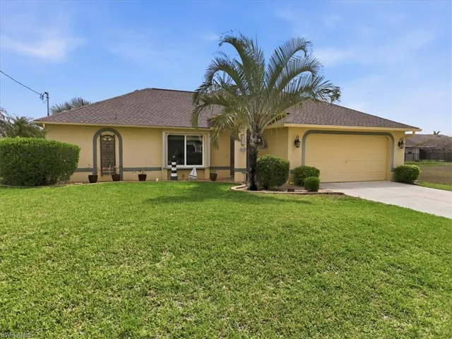 Ranch-style house featuring an attached garage, stucco siding, a front lawn, and driveway