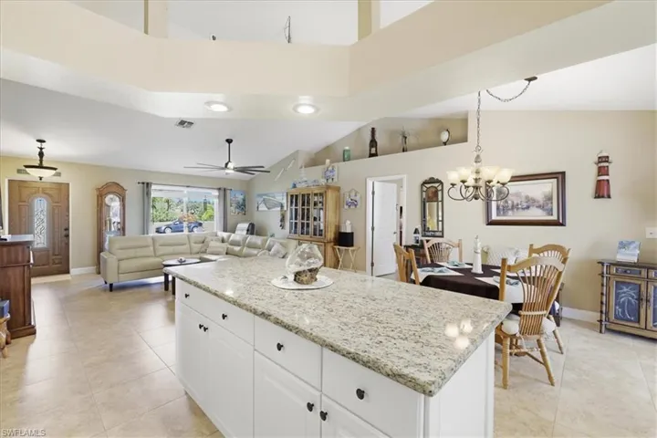 Kitchen with a center island, white cabinets, light stone countertops, a ceiling fan, and open floor plan