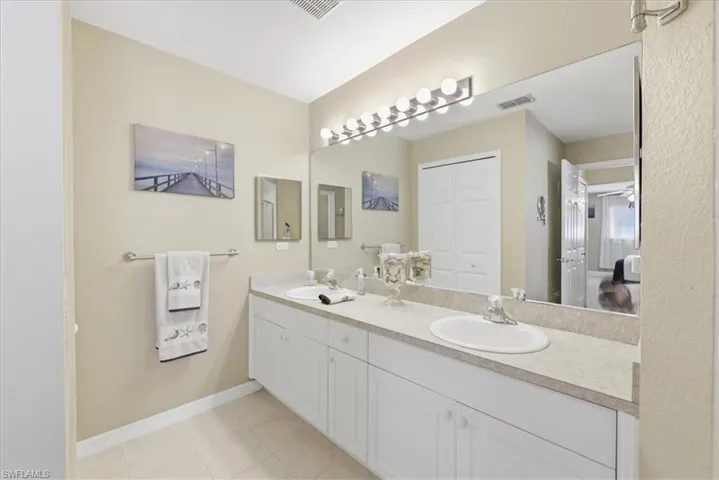 Full bath with double vanity, light tile patterned floors, and a closet