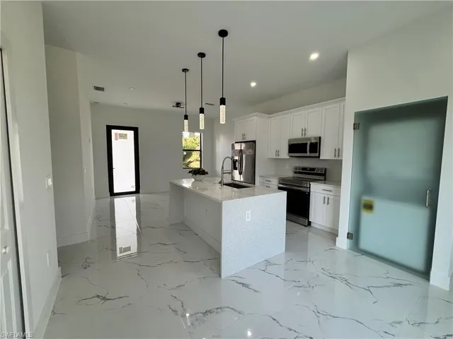 Kitchen featuring recessed lighting, white cabinets, marble finish floor, stainless steel appliances, and a sink