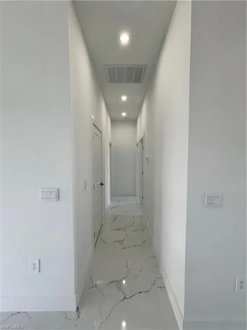 Hall with recessed lighting, baseboards, visible vents, and marble finish floor