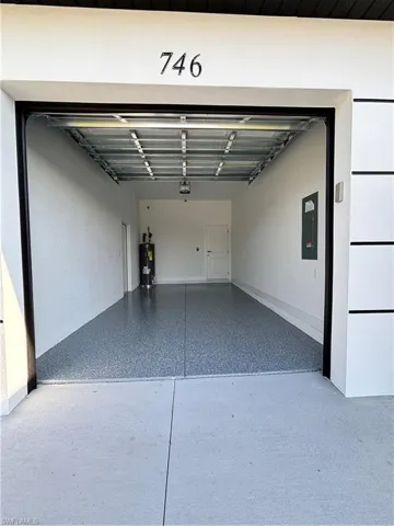 Garage featuring water heater, a garage door opener, and electric panel