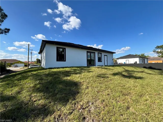 Rear view of property featuring a yard and stucco siding