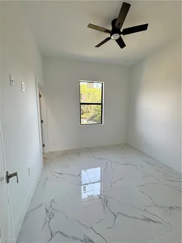 Spare room with a ceiling fan and marble finish floor