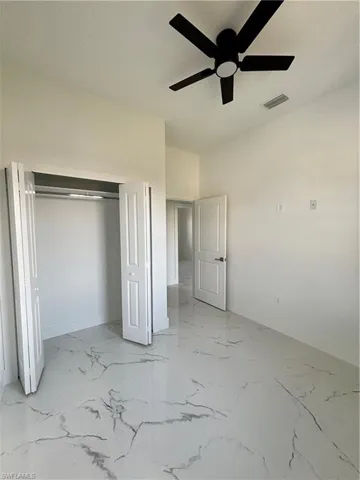 Unfurnished bedroom featuring a closet, marble finish floor, a ceiling fan, and visible vents