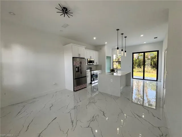 Kitchen with visible vents, marble finish floor, open floor plan, white cabinetry, and appliances with stainless steel finishes