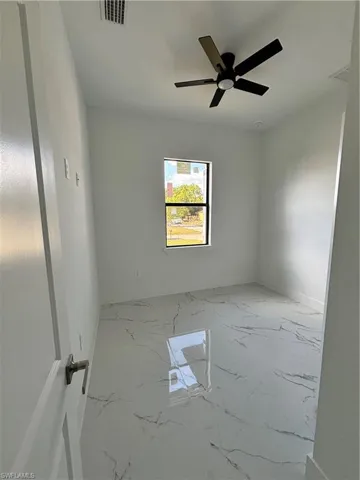 Unfurnished room with visible vents, marble finish floor, and ceiling fan