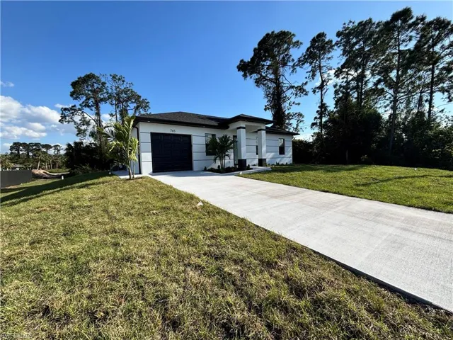 View of front facade with stucco siding, driveway, a front lawn, and an attached garage
