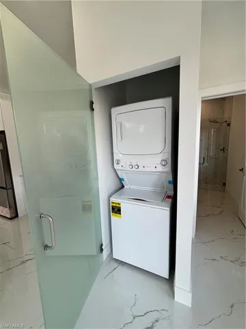 Laundry room featuring laundry area, marble finish floor, and stacked washer / drying machine