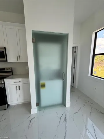 Kitchen with stove, marble finish floor, and white cabinets