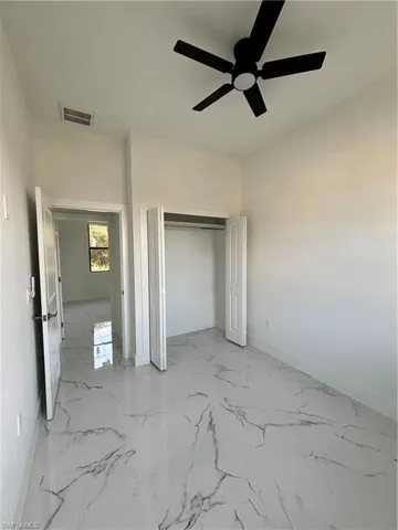 Unfurnished bedroom featuring visible vents, marble finish floor, a closet, baseboards, and ceiling fan