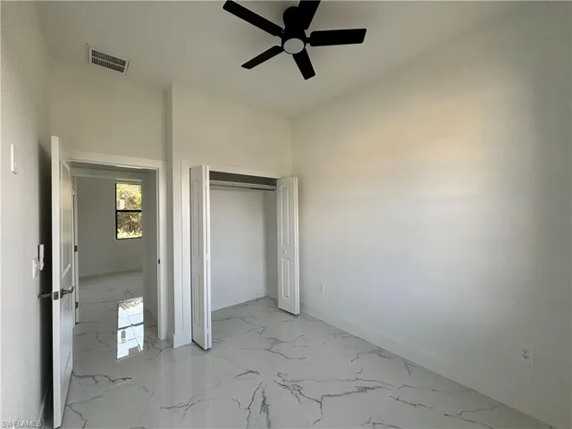 Unfurnished bedroom with visible vents, marble finish floor, a ceiling fan, a closet, and baseboards