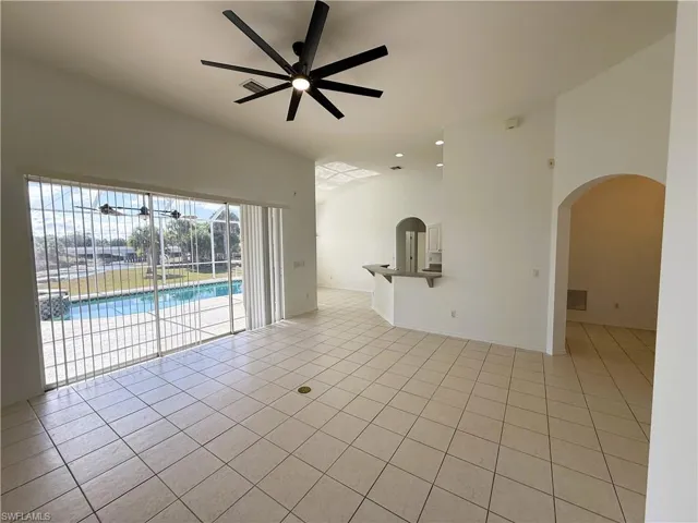 Spare room with a ceiling fan, light tile patterned floors, high vaulted ceiling, and arched walkways