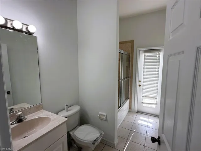 Full bath with vanity, light tile patterned floors, and shower / bath combination with glass door