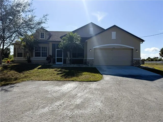 Ranch-style home with a front lawn, driveway, an attached garage, stone siding, and stucco siding