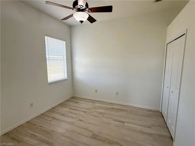 Unfurnished bedroom featuring light wood-style flooring, a closet, and ceiling fan