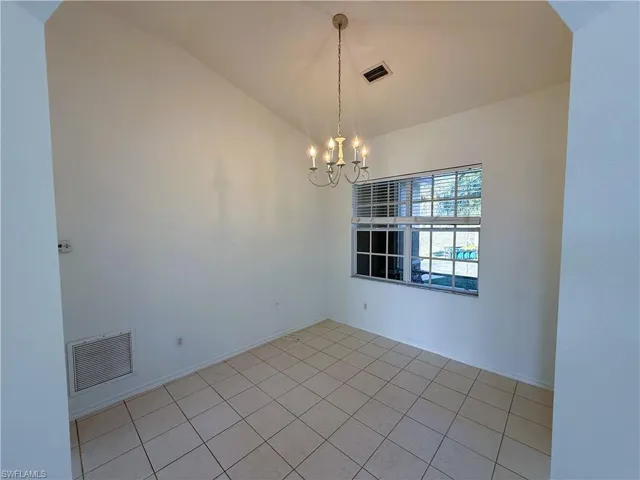 Spare room featuring a chandelier, lofted ceiling, and light tile patterned flooring