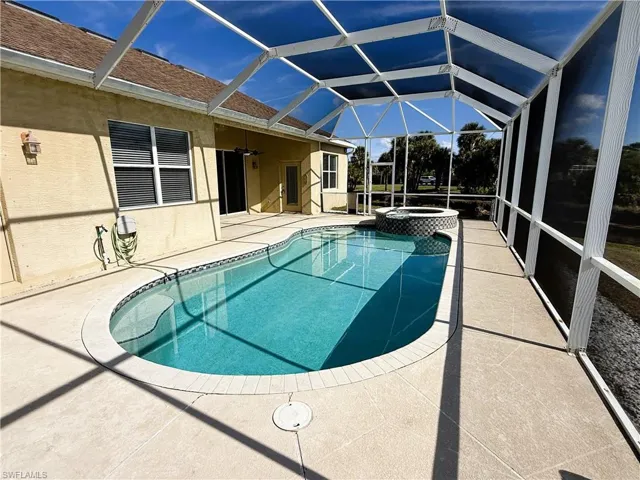 View of swimming pool with a patio area, a sunroom, glass enclosure, and a pool with connected hot tub