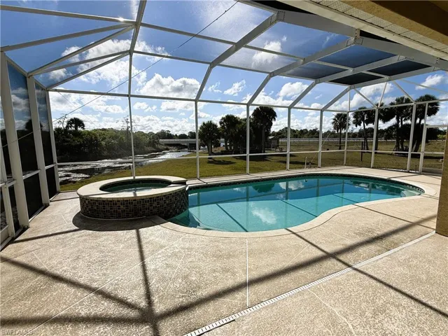 View of swimming pool with a sunroom, glass enclosure, and a patio area