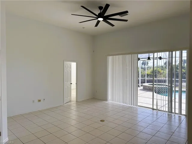 Empty room with light tile patterned flooring, a ceiling fan, and a towering ceiling
