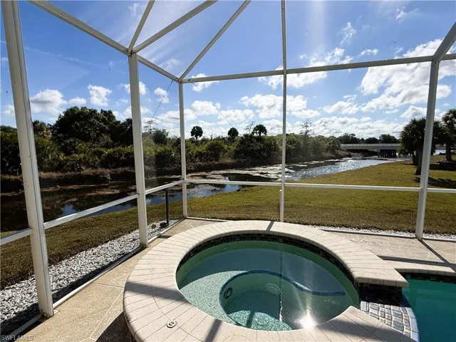View of pool with a lanai, a sunroom, a lawn, an in-ground hot tub, and a water view