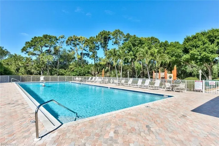 Community pool featuring a patio and view of wooded area