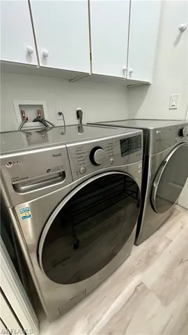 Washroom with washer and dryer, cabinet space, and light wood-type flooring