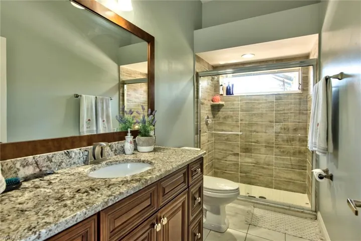 Full bath with vanity, a shower stall, and light tile patterned floors