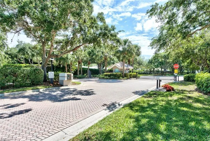 View of home's community featuring a gate, view of wooded area, and driveway