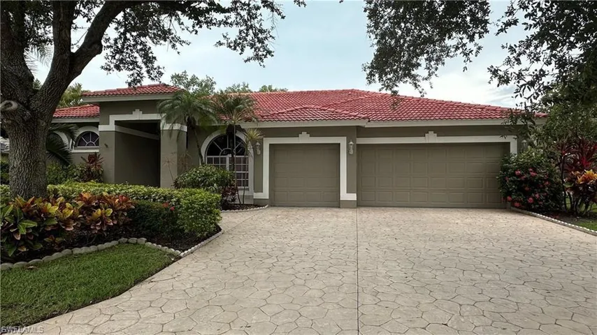 View of front of house with decorative driveway, stucco siding, an attached garage, and a tile roof