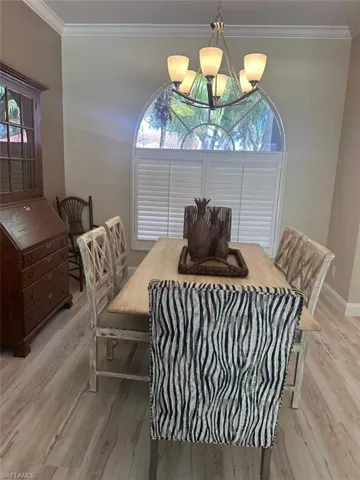 Dining room featuring crown molding, light wood-type flooring, plenty of natural light, and a chandelier