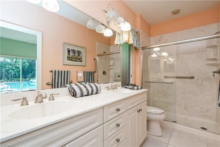 Bathroom with an enclosed shower, vanity, tile patterned floors, and toilet