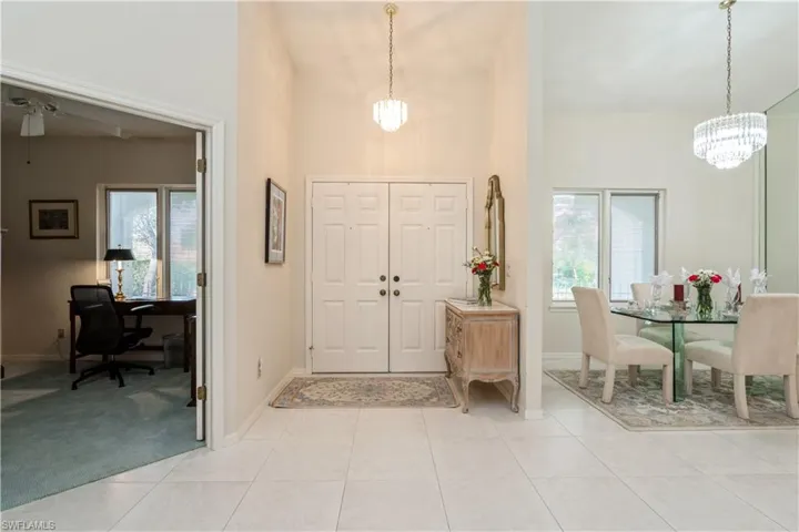Entryway with a healthy amount of sunlight, light tile patterned floors, and a notable chandelier