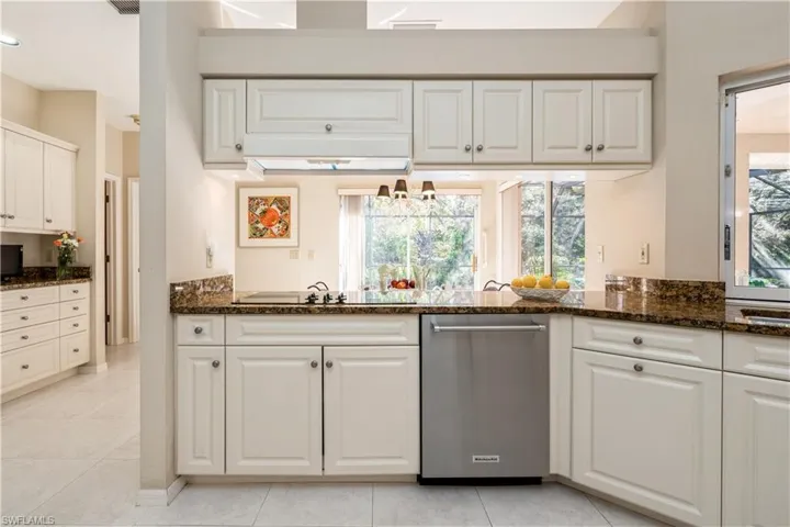 Kitchen with electric cooktop, dark grantie counters, light tile patterned floors, and white cabinets