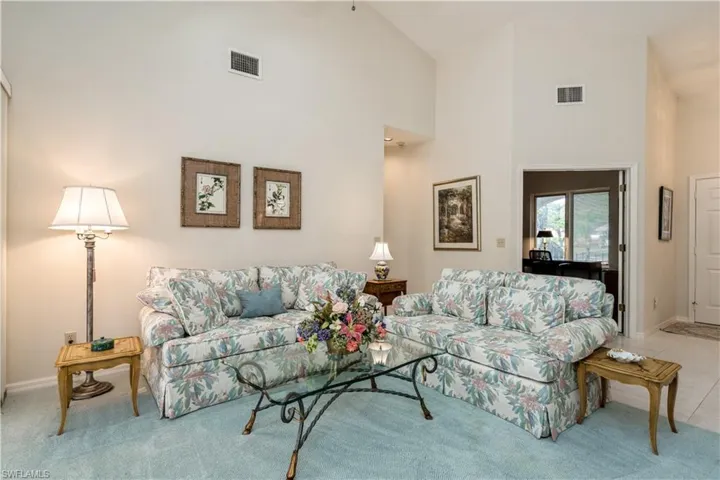 Tiled living room featuring high vaulted ceiling