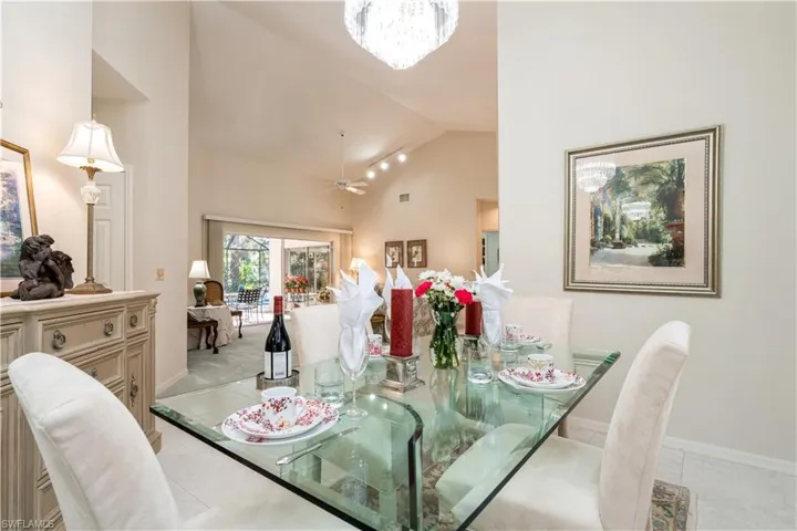 Tiled dining room with ceiling fan with notable chandelier and high vaulted ceiling