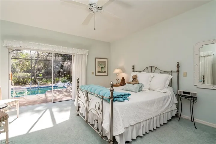 Carpeted bedroom with access to exterior pool and deck and ceiling fan