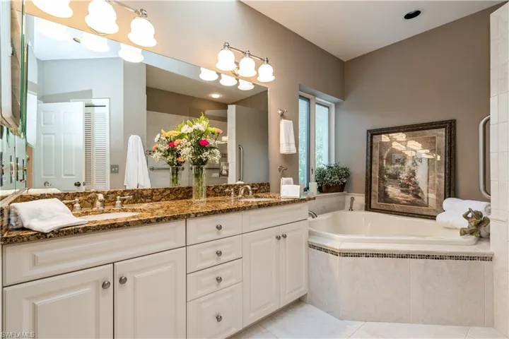 Primary bathroom with vanity, tiled bath, and tile patterned flooring